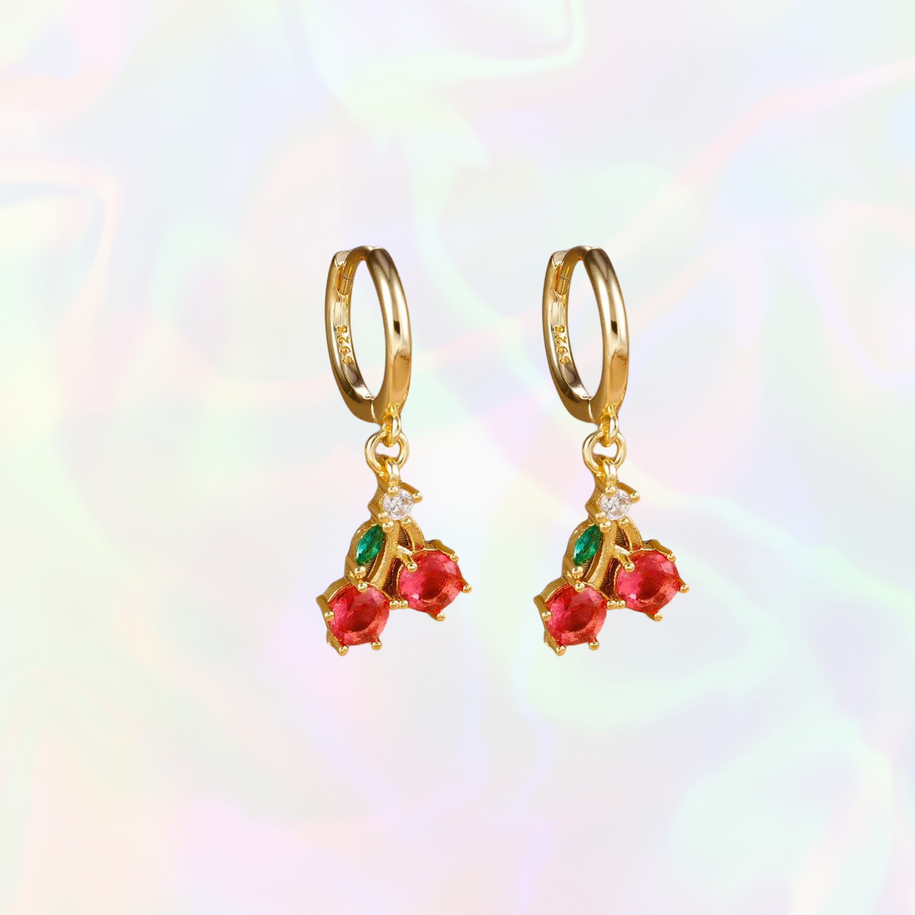 Gold cherry earrings with red and green gemstones on a colorful background