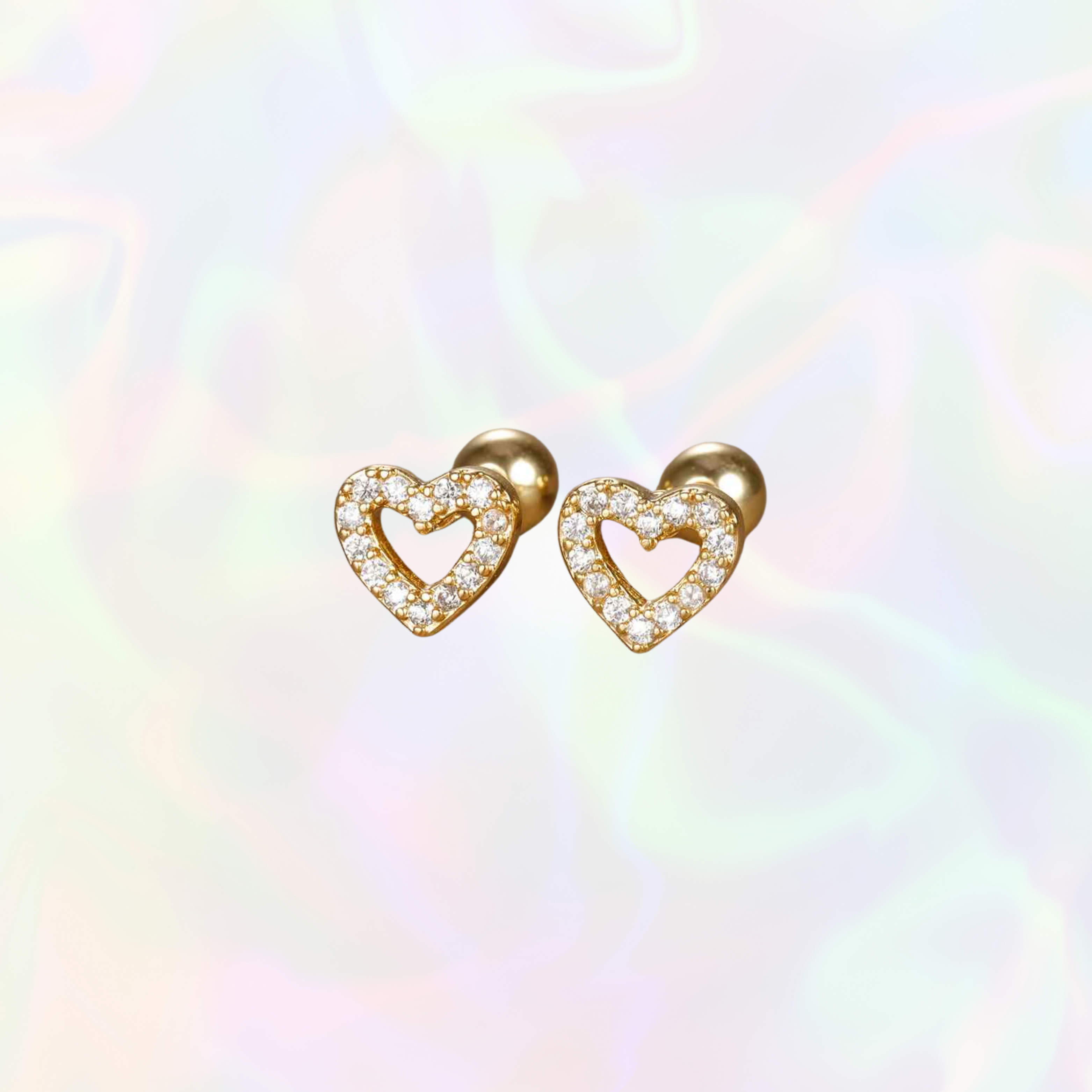 Heart-shaped gold earrings with clear stones on a multicolored background
