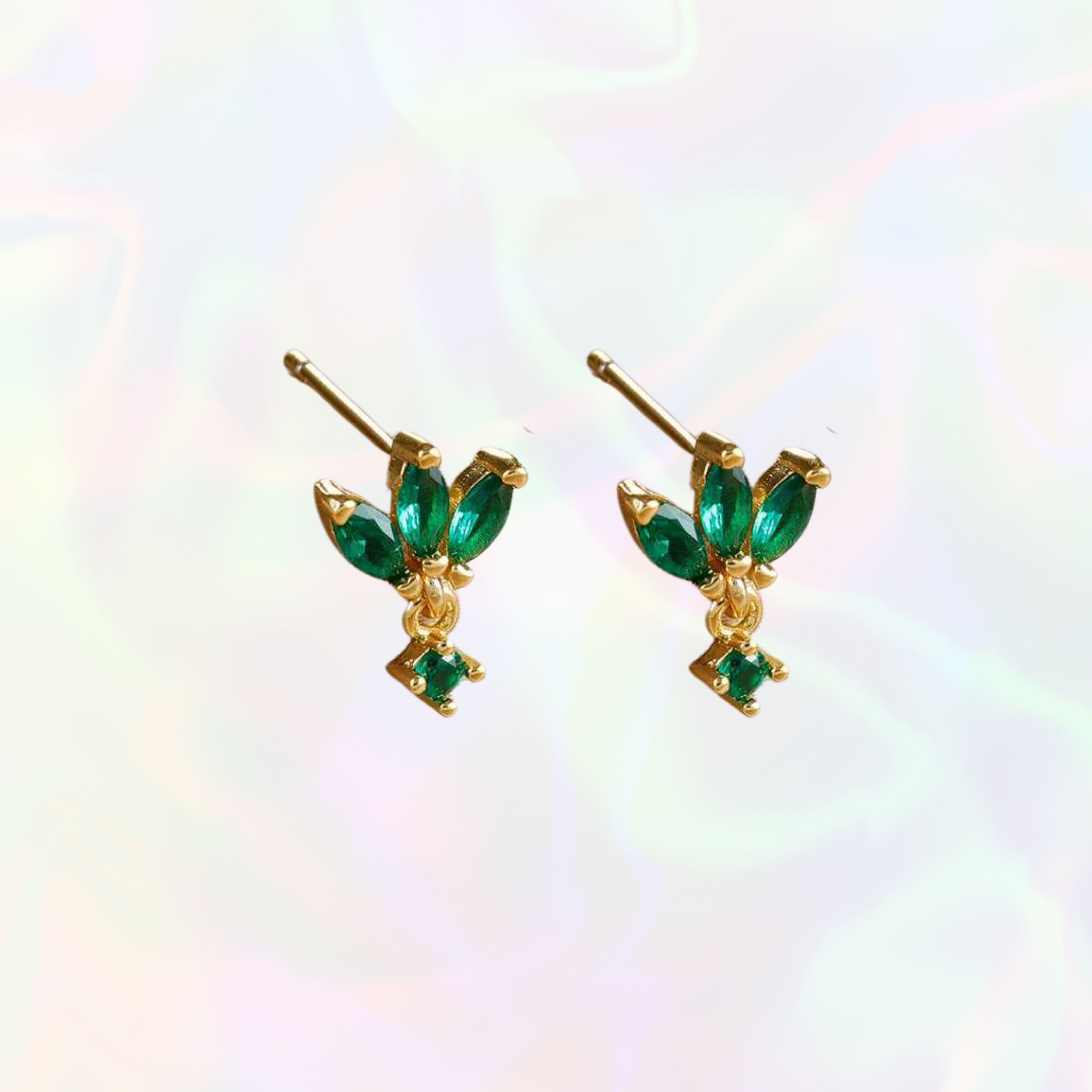 Gold earrings with emerald green gemstones on a white background
