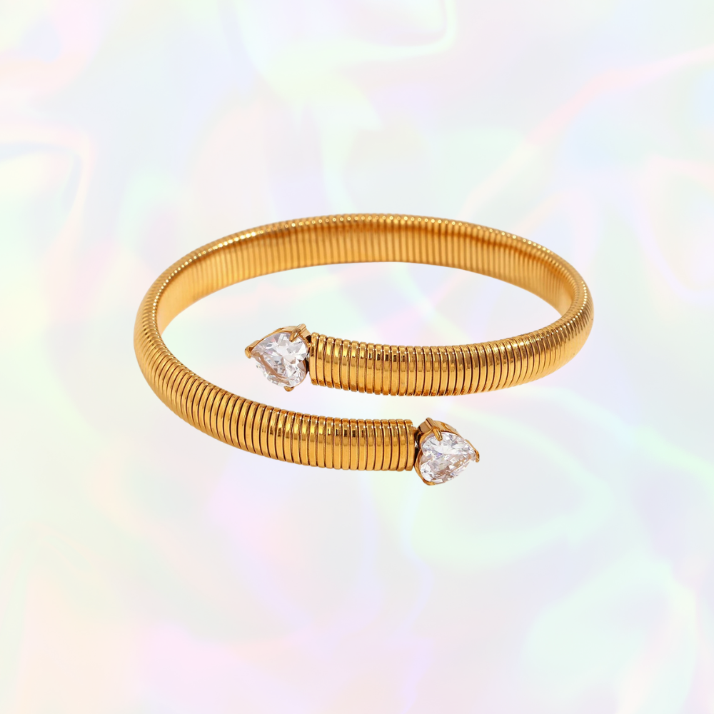 Gold hypoallergenic bracelet with heart-shaped gemstones on a multicolored background