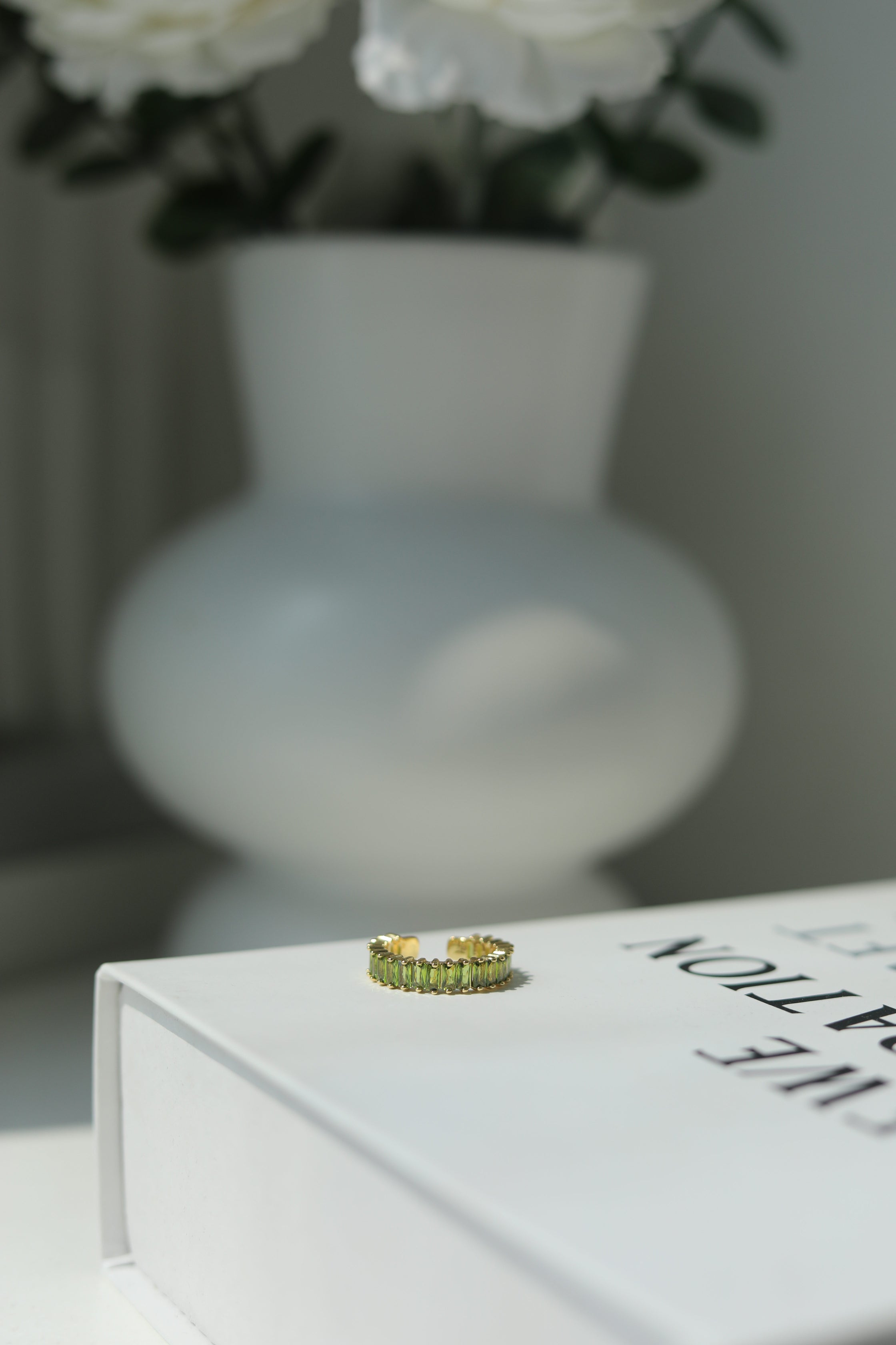 Green ring on a book with a blurred vase and flowers in the background