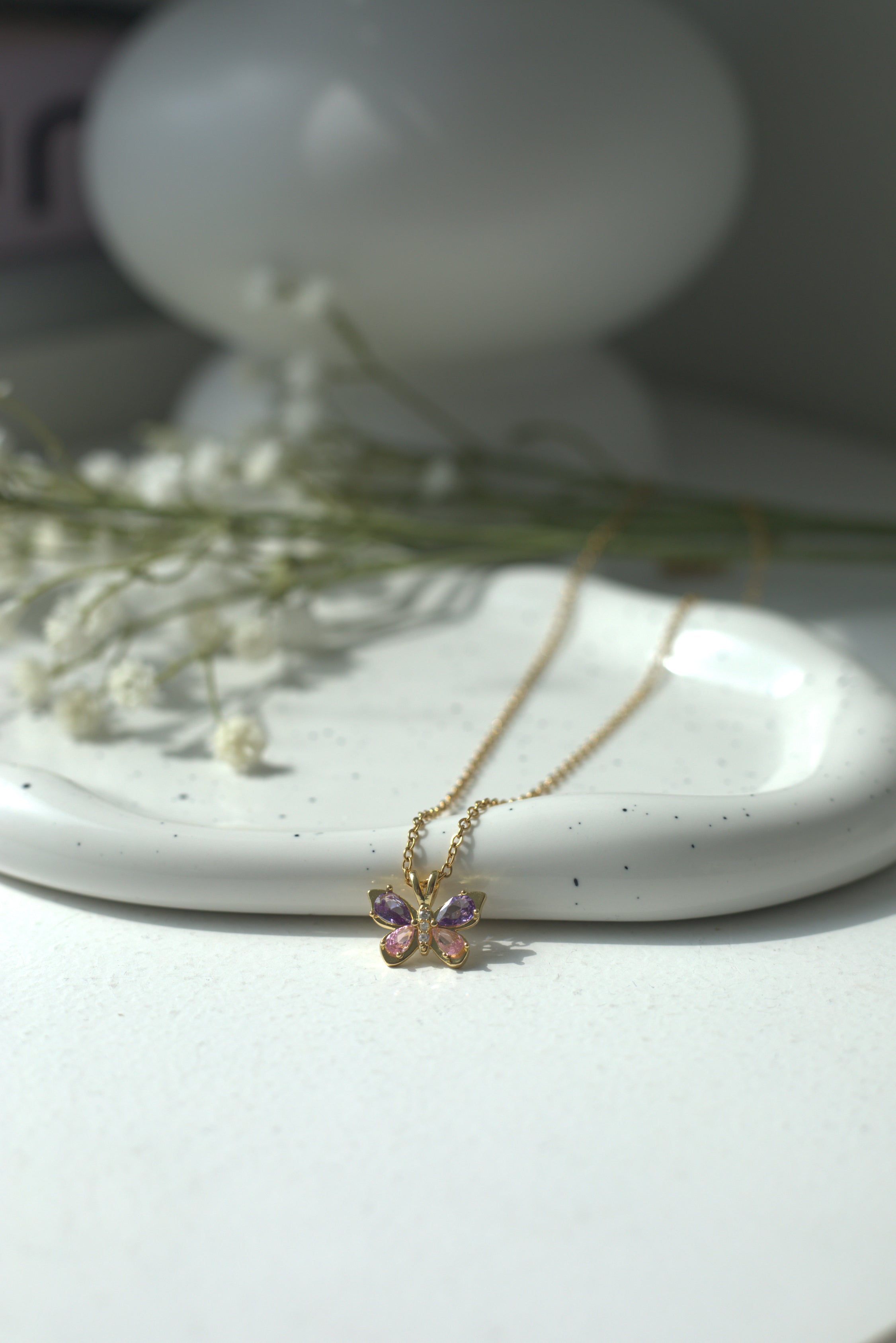 Delicate butterfly purple necklace on a white surface with blurred background