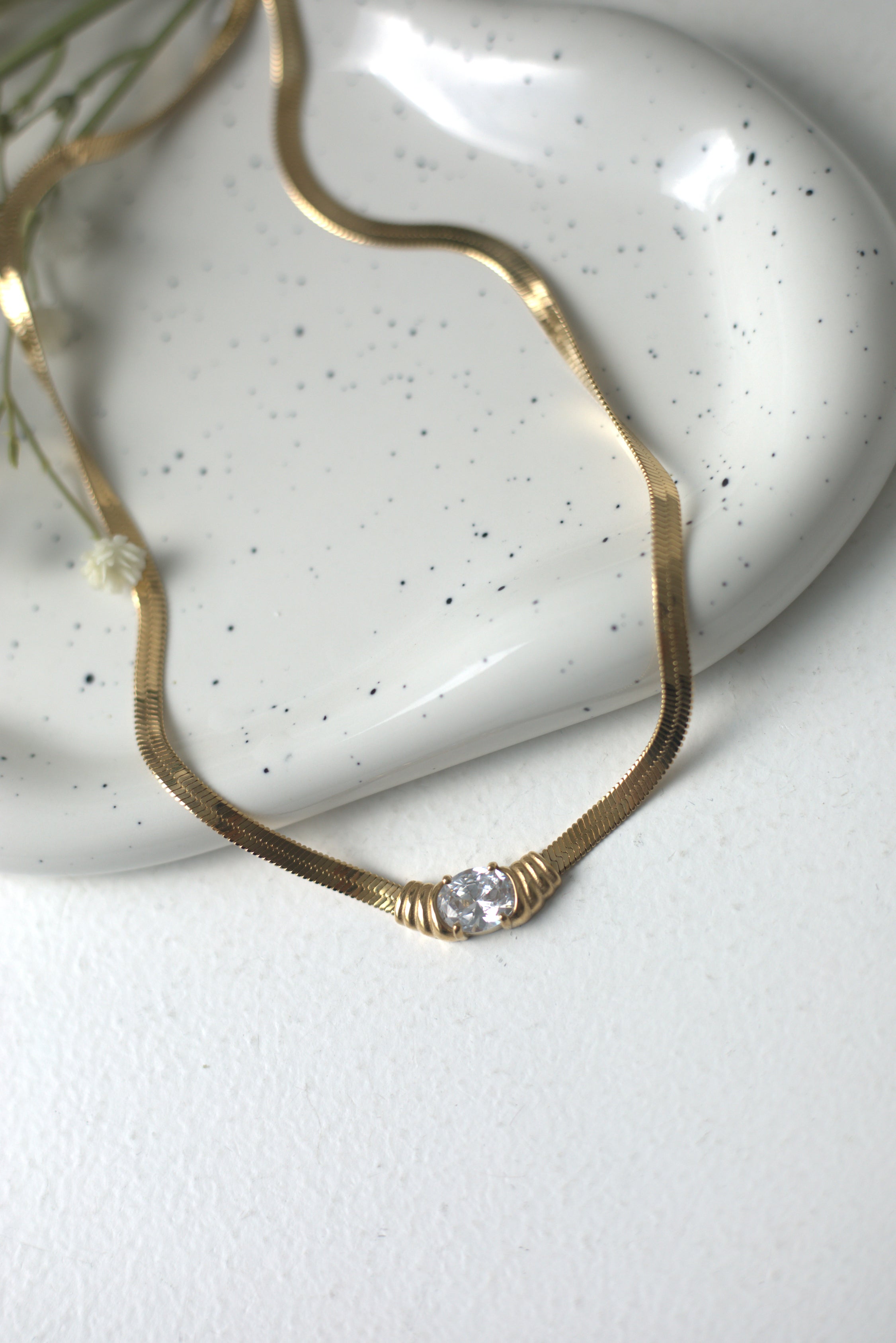 Elegant gold necklace with a diamond pendant on a white surface