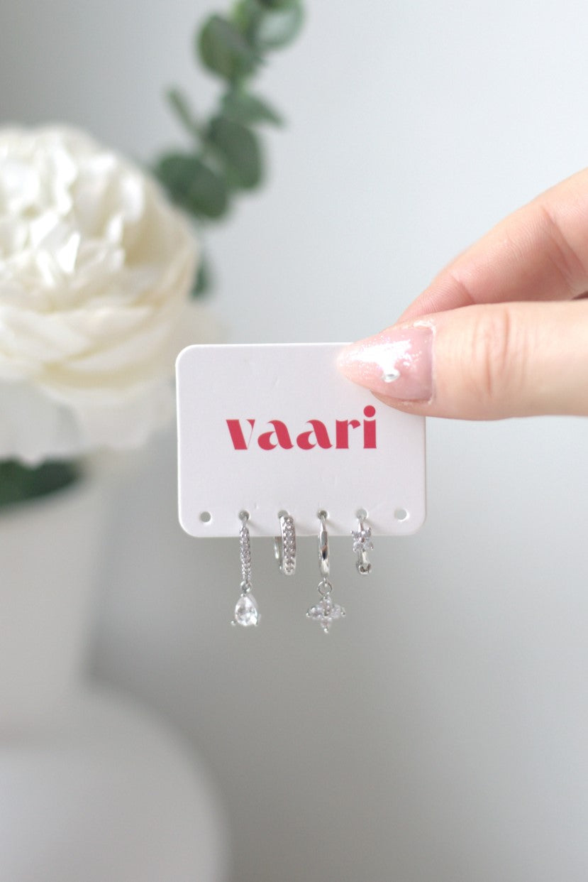 Hand holding a card with 'vaari' brand name and a set of silver earrings on a light background