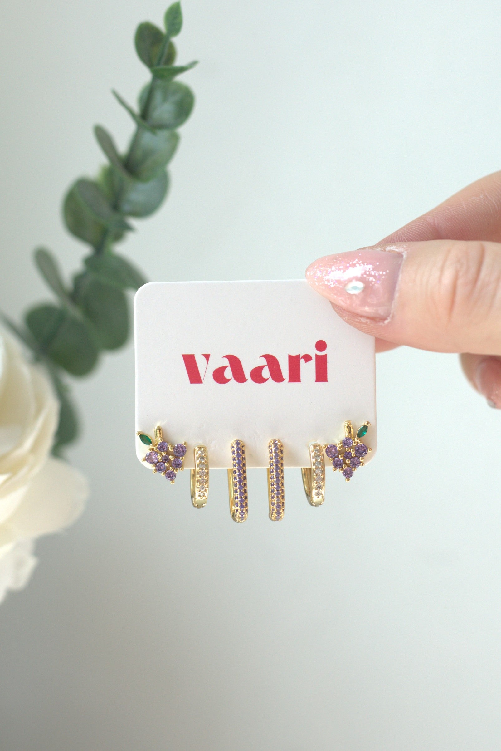 Earring display card with gold square hoop earrings in purple accents on a white background