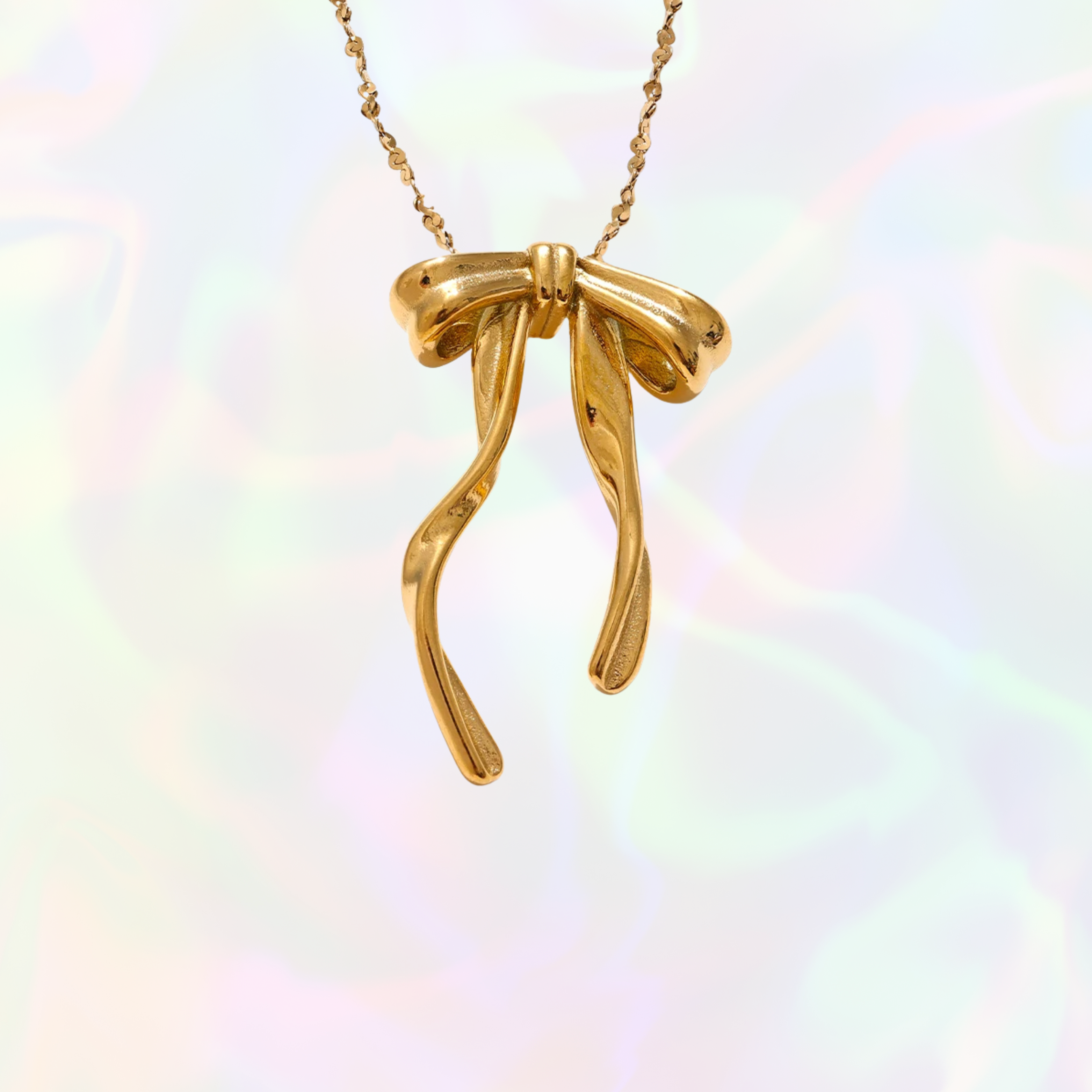 Gold bow-shaped pendant on a chain against a rainbow gradient background