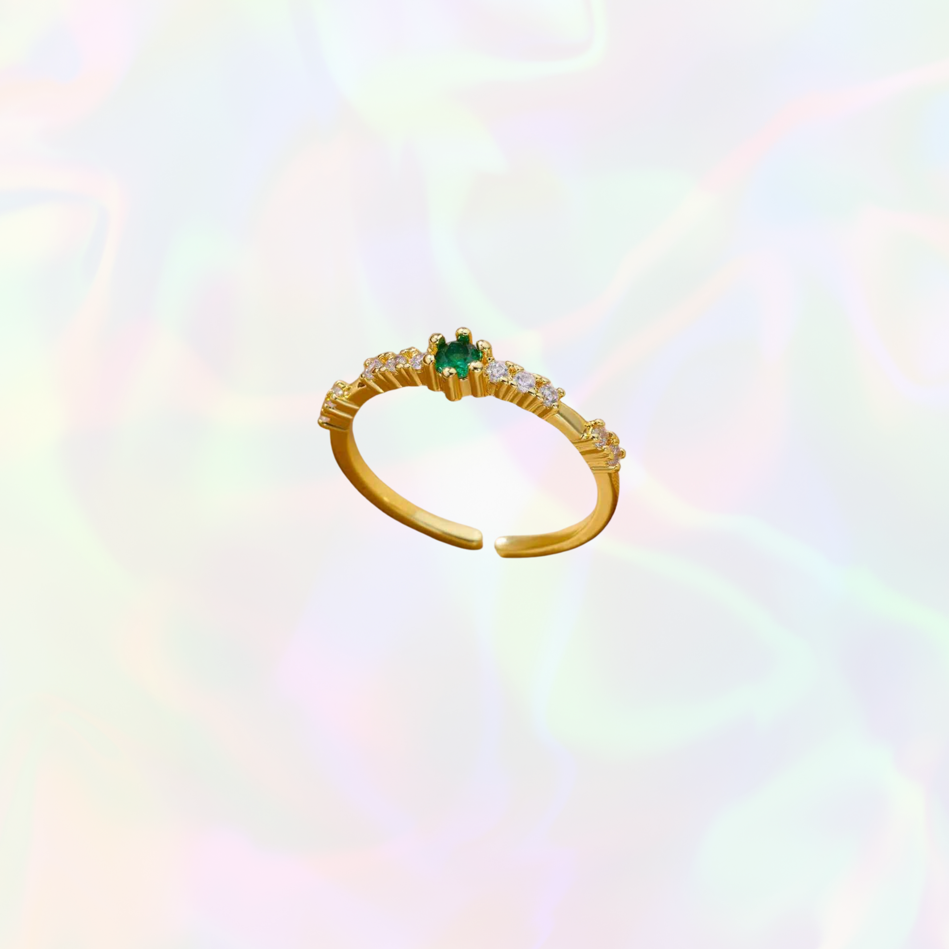 Gold ring with a green gemstone on a rainbow gradient background
