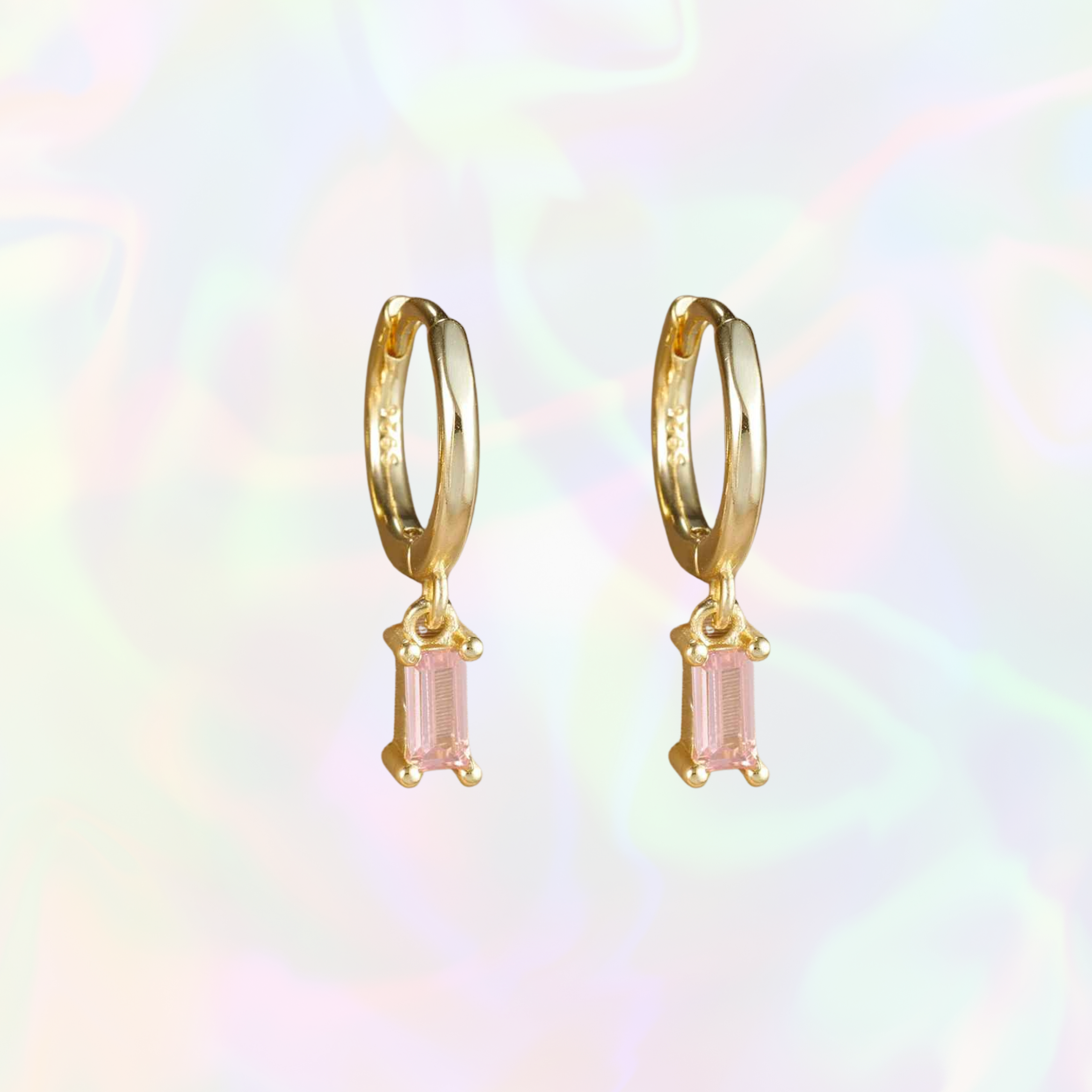 Gold hoop earrings with pink gemstones on a multicolored background