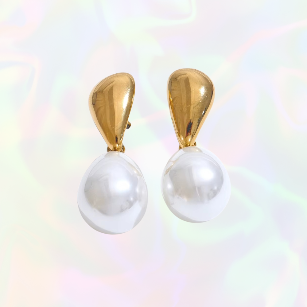 Pearl earrings with gold tops on a multicolored background