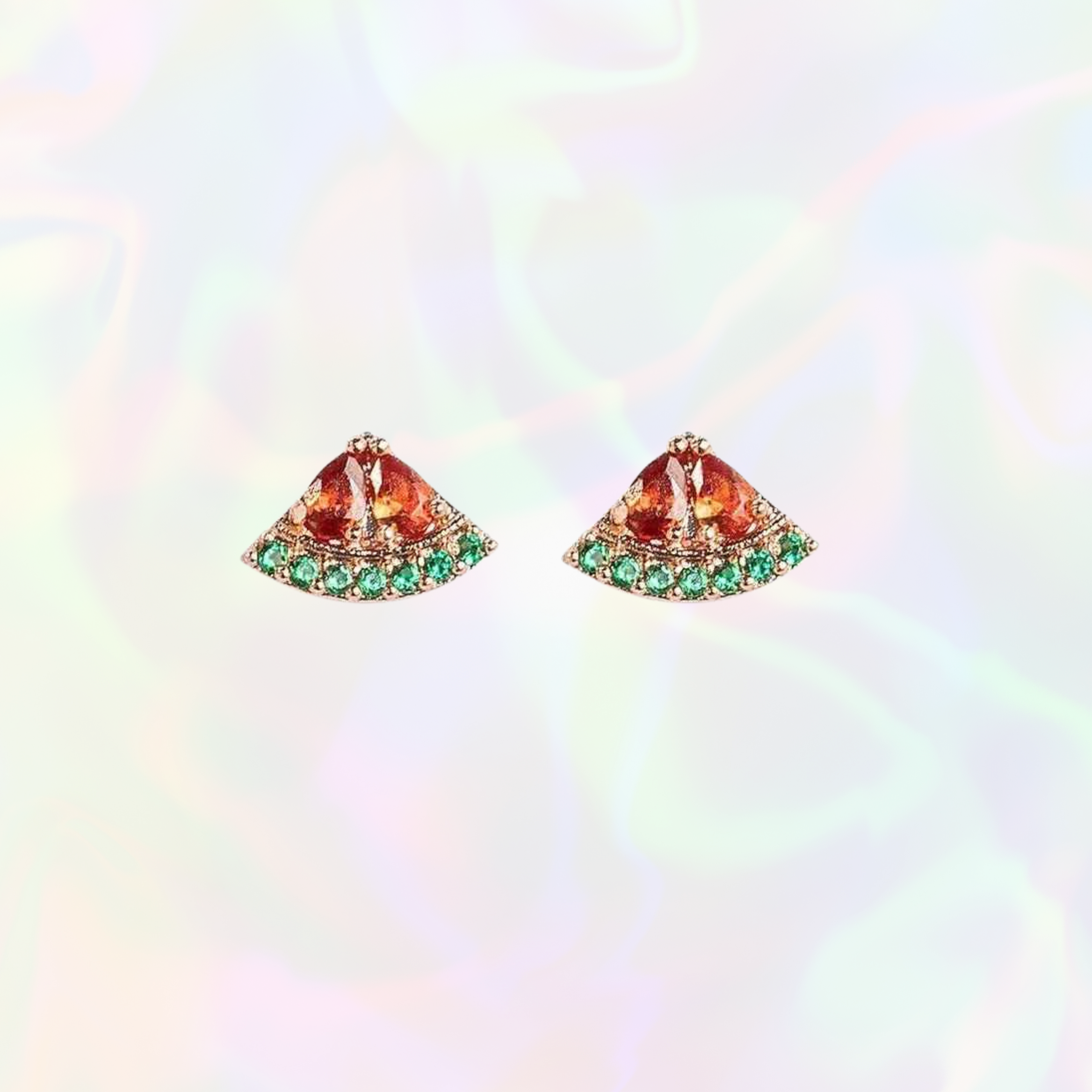 Pair of watermelon earrings with orange gemstones and green accents on a rainbow gradient background