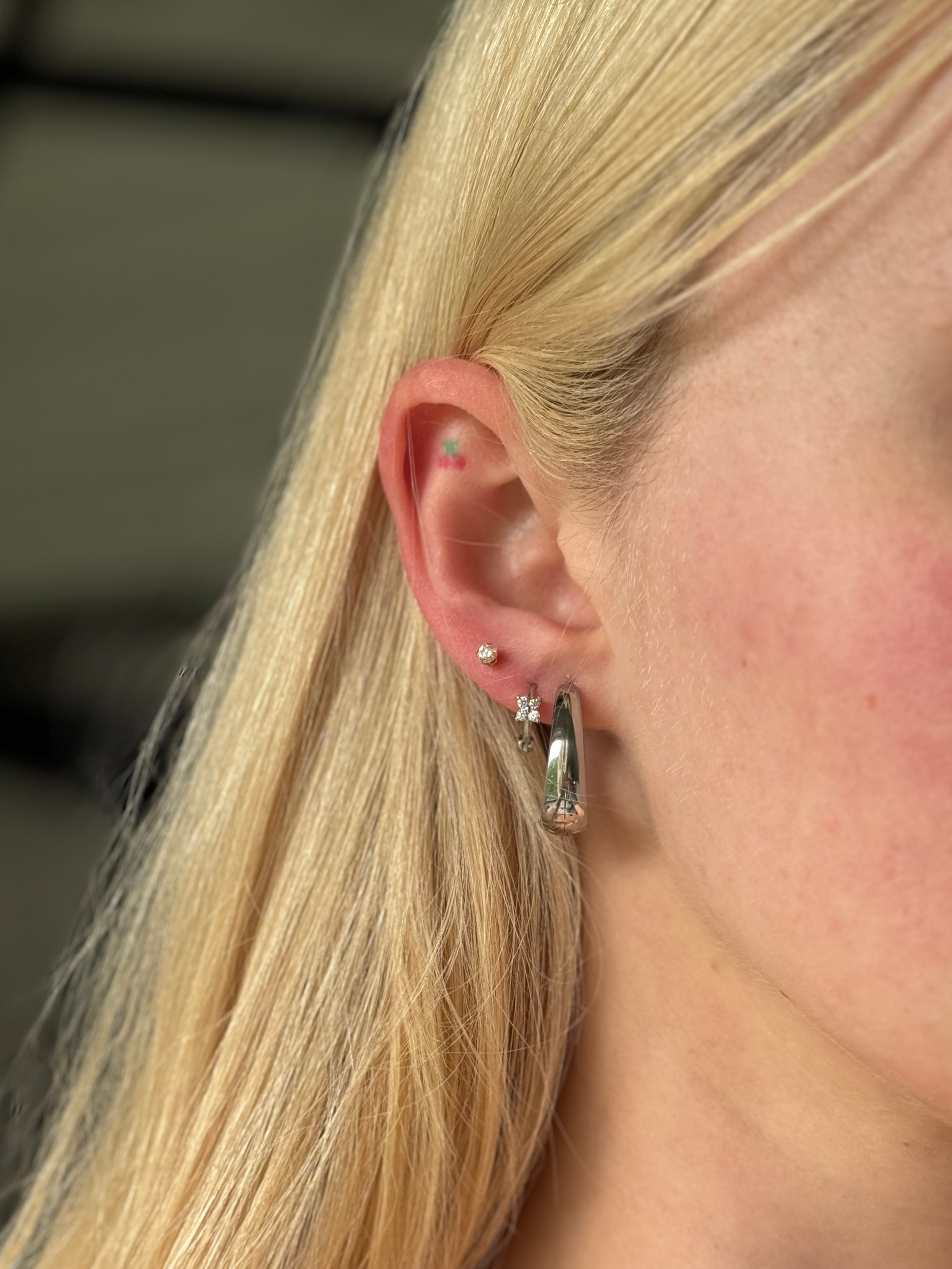 Close-up of a person wearing a waterproof silver hoop earring with a blurred background
