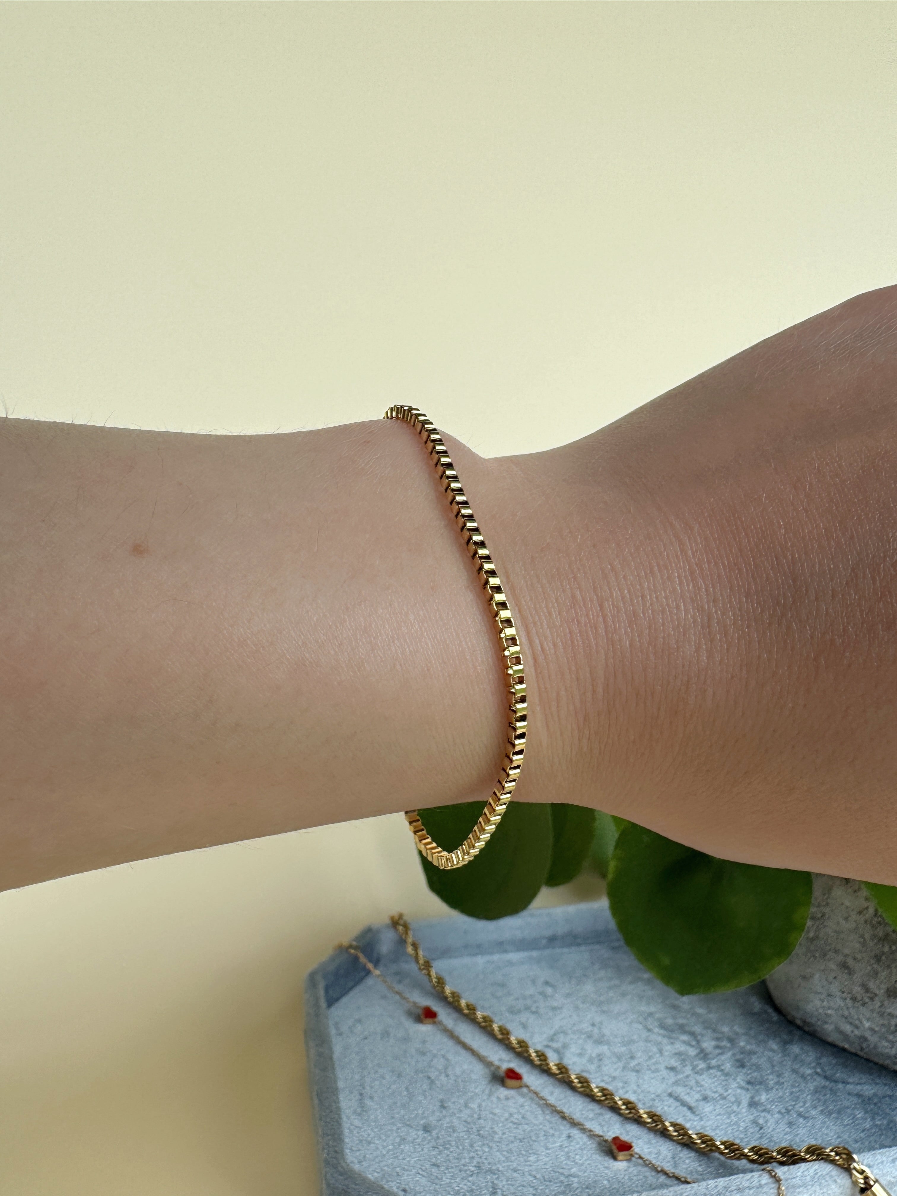 Simple gold bracelet on a wrist with a neutral background
