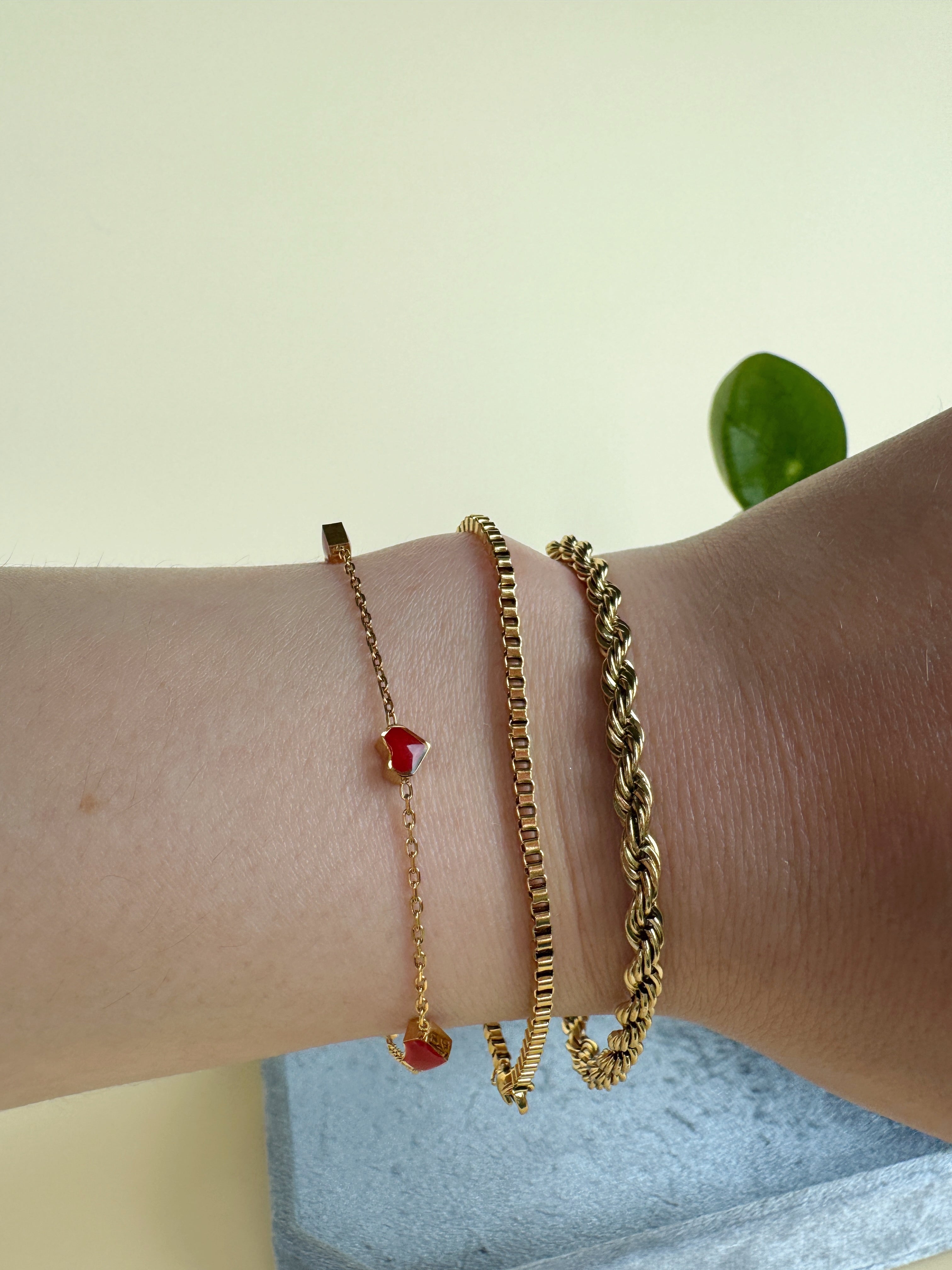 Three gold bracelets on a wrist with a light background