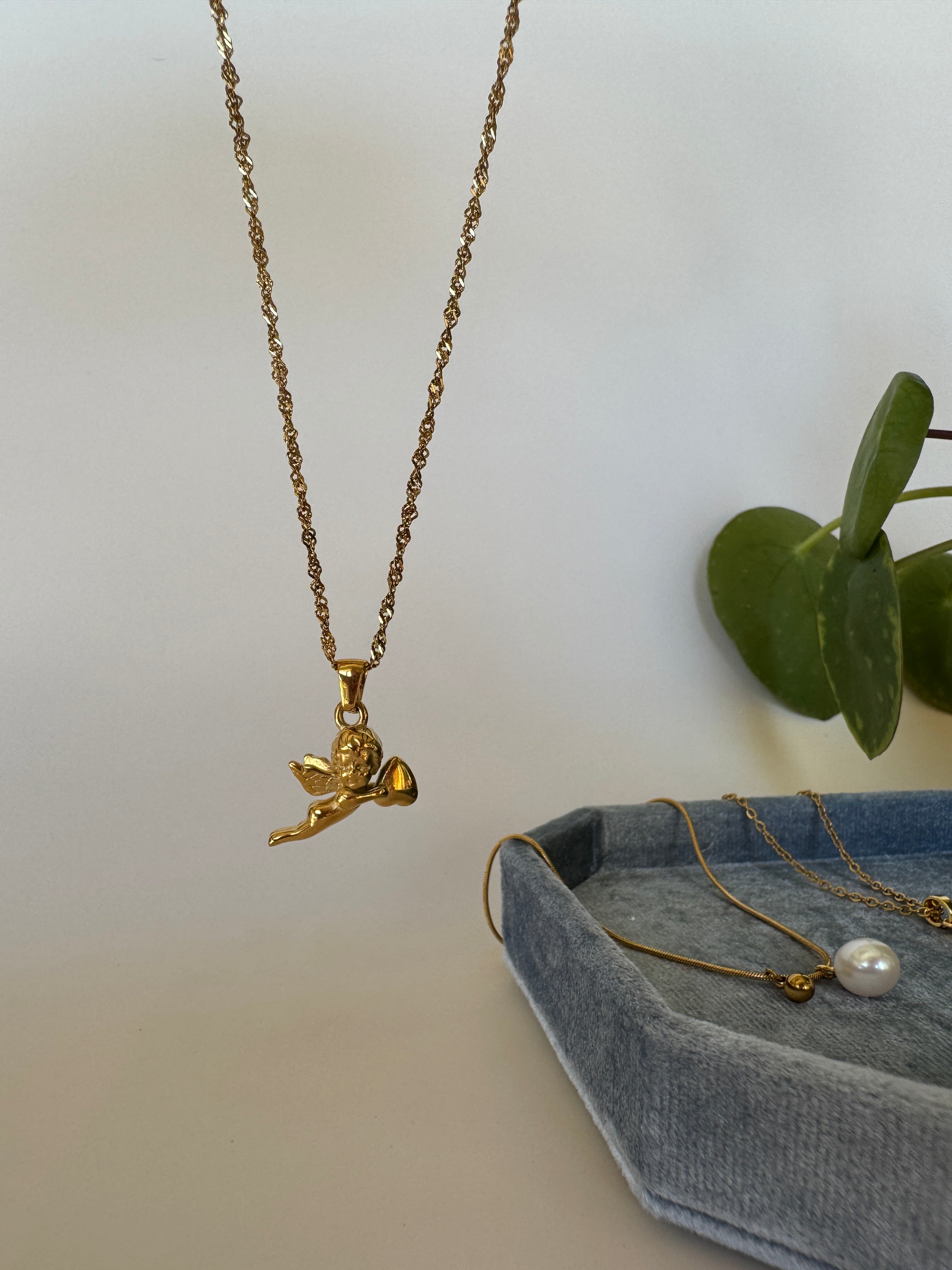 Gold necklace with a good luck in love cupid pendant on a light background