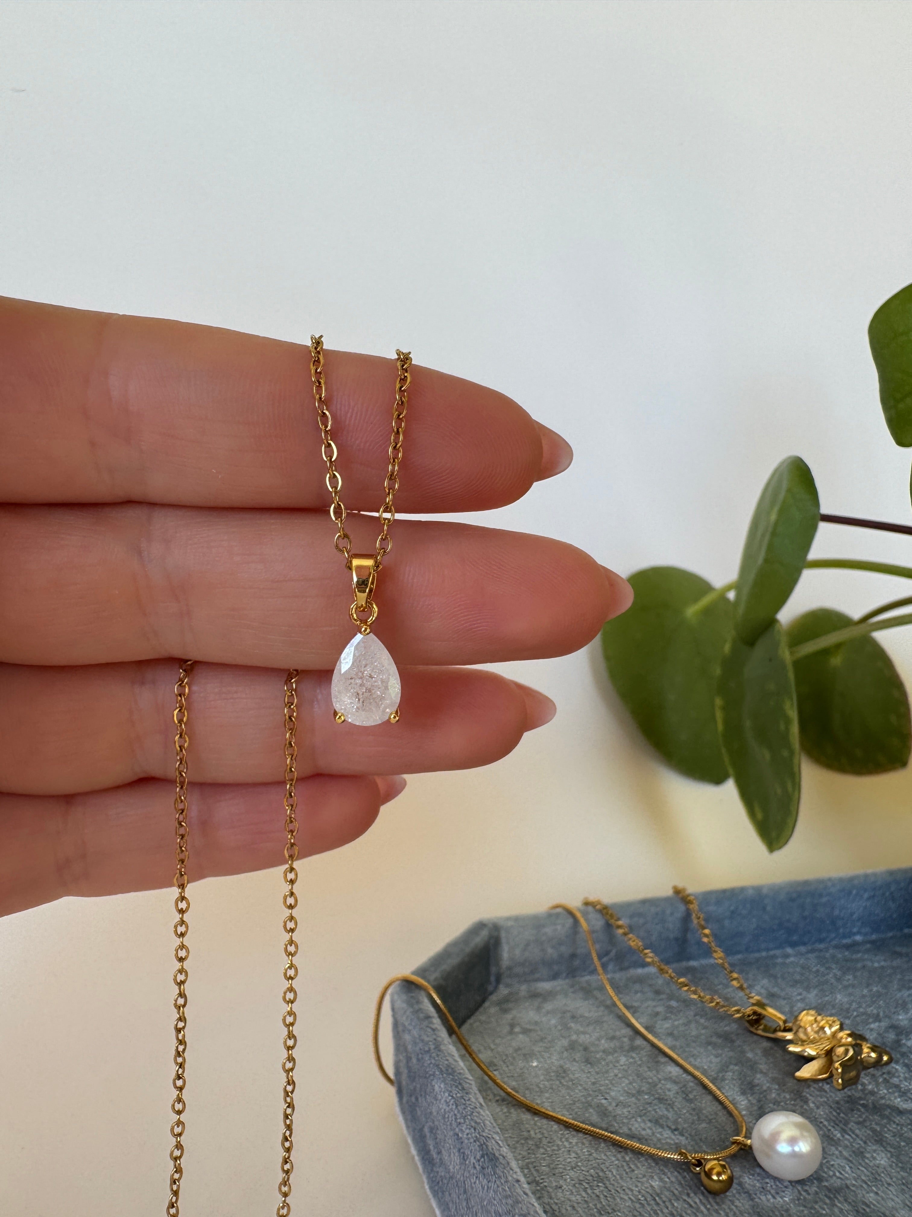 Gold necklaces with pendants on a hand against a light background