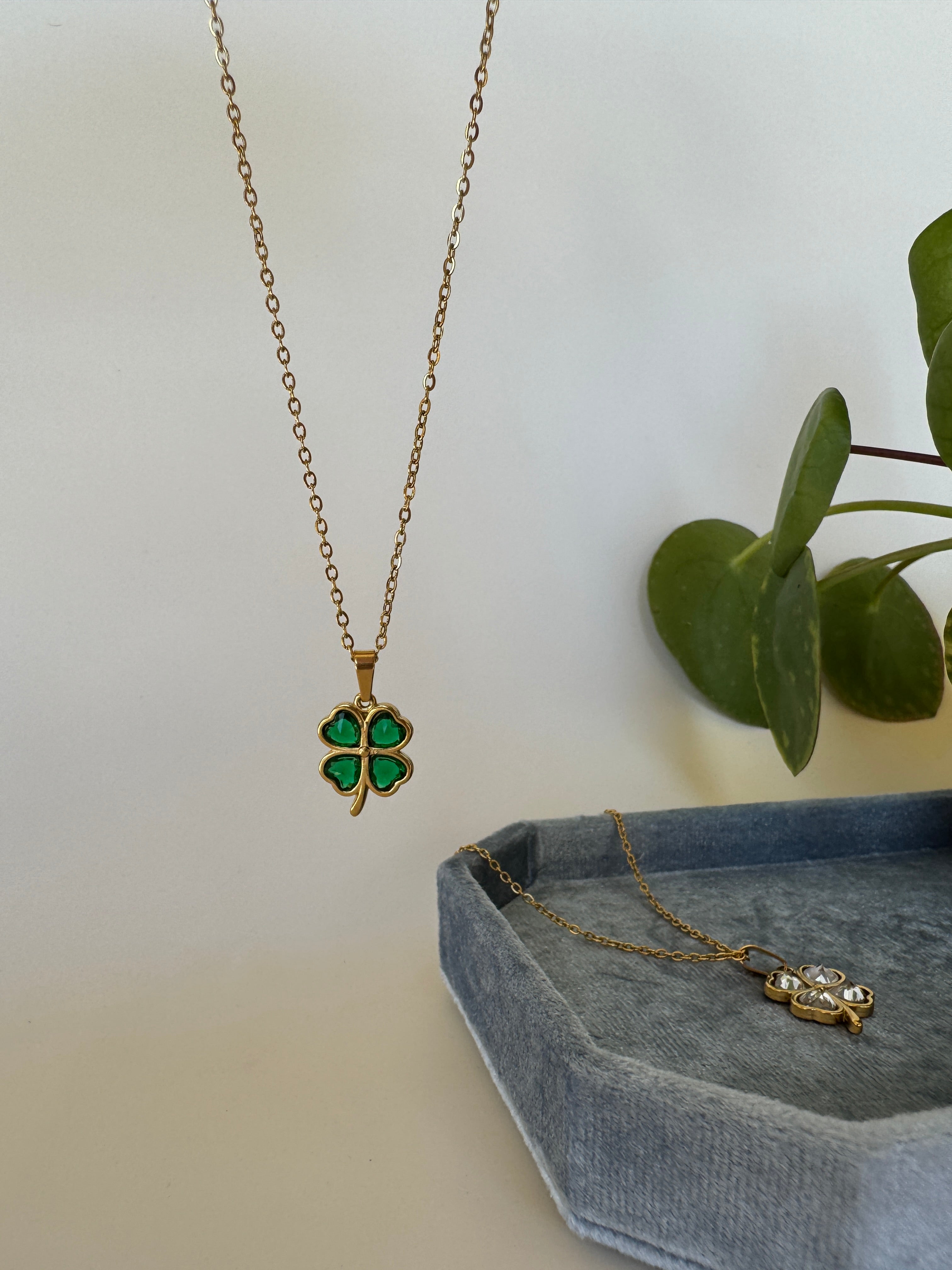 Gold good luck necklace with green gemstones on a white background
