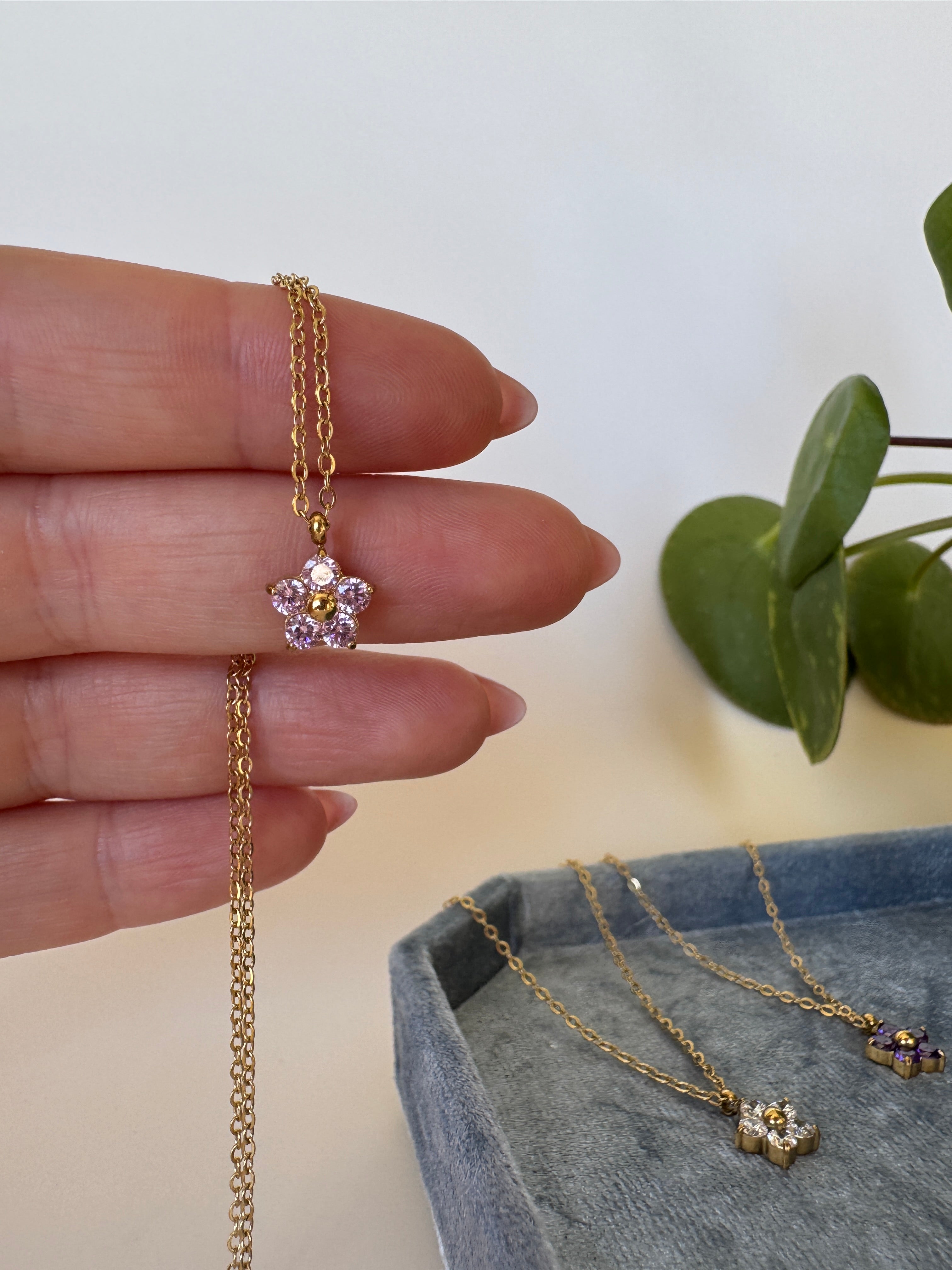 Gold stainless steel necklace with pink floral design on a neutral background