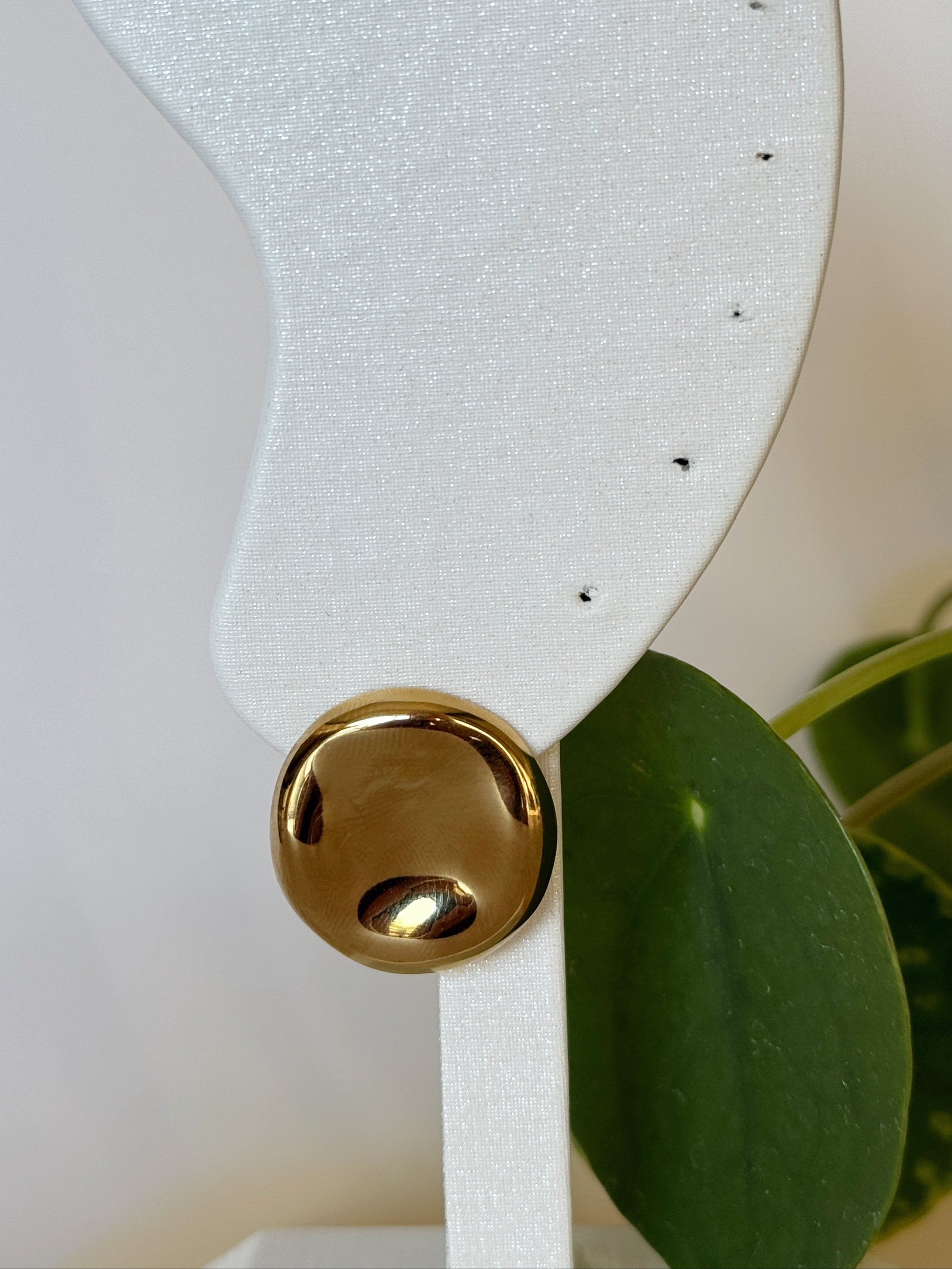 White paddle with gold classic earring on a light background