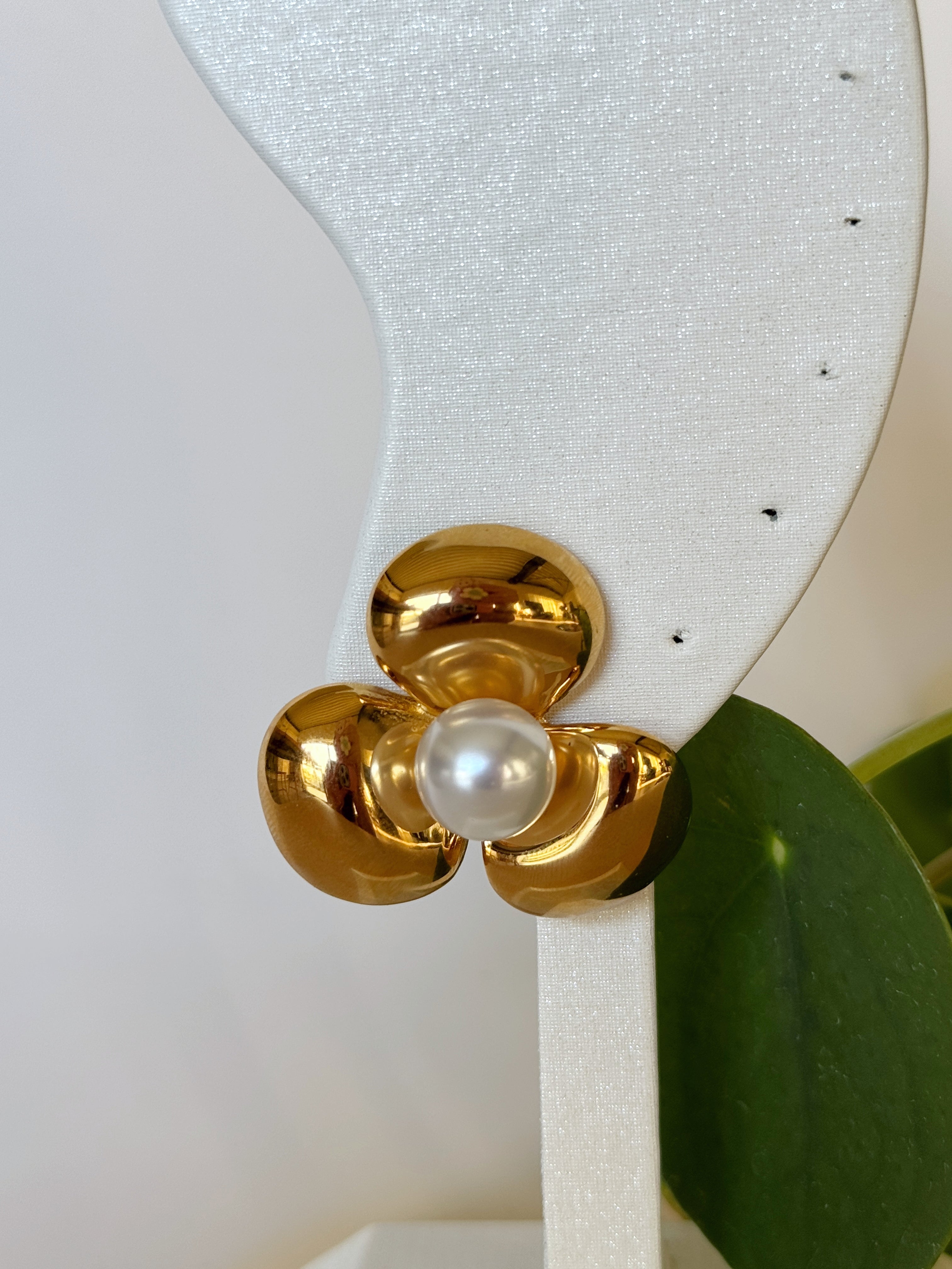 Bold gold earring with a pearl on a white background