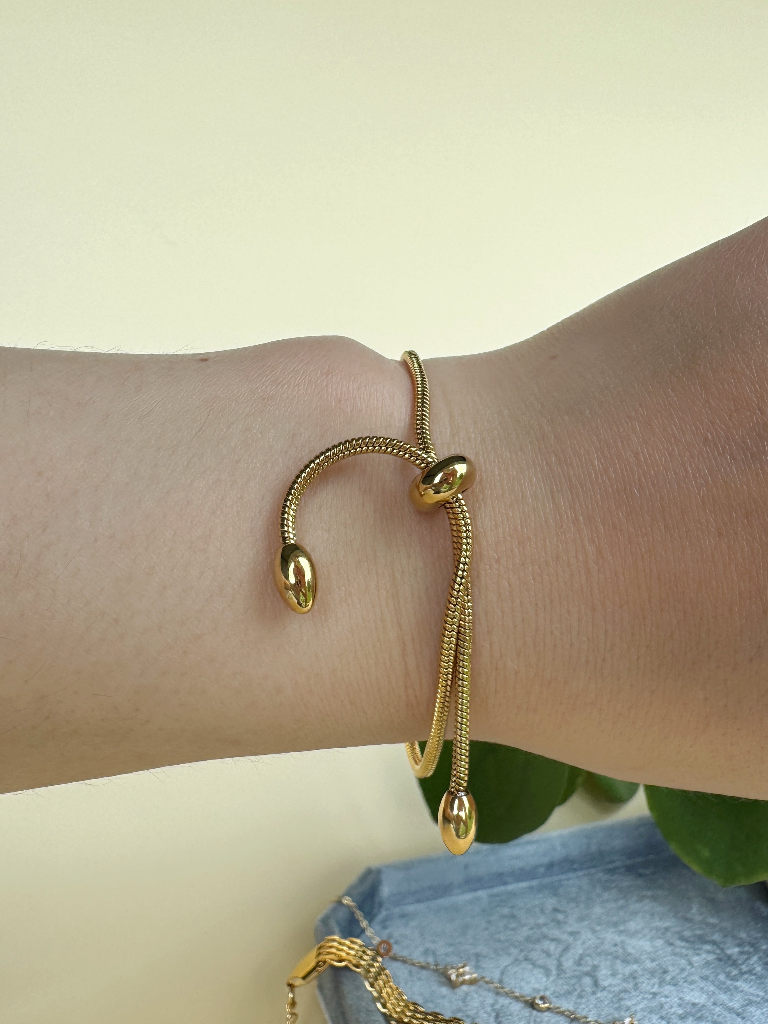 Gold bracelet on a wrist with a light background