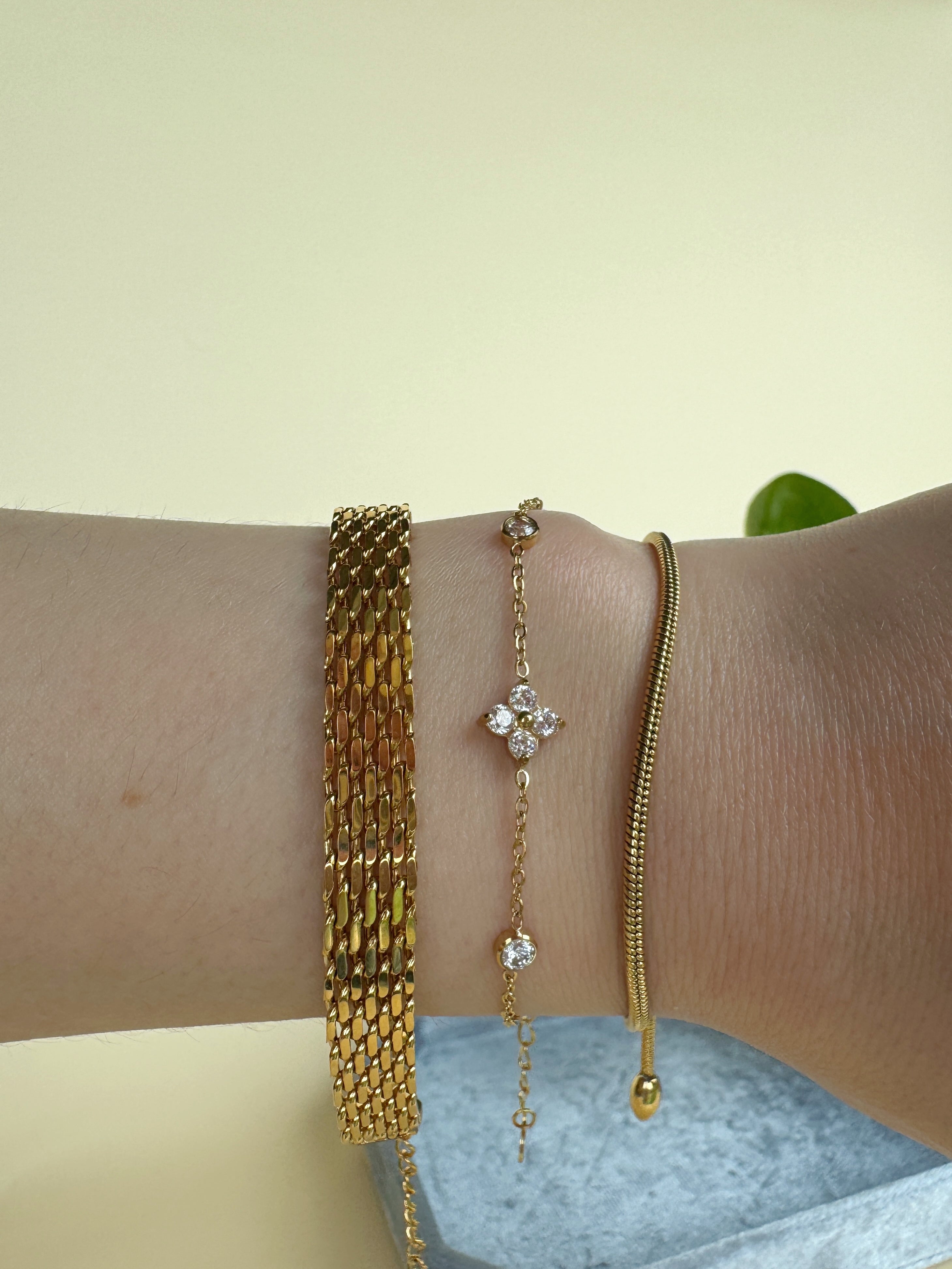 Gold bracelets on a wrist with a light background