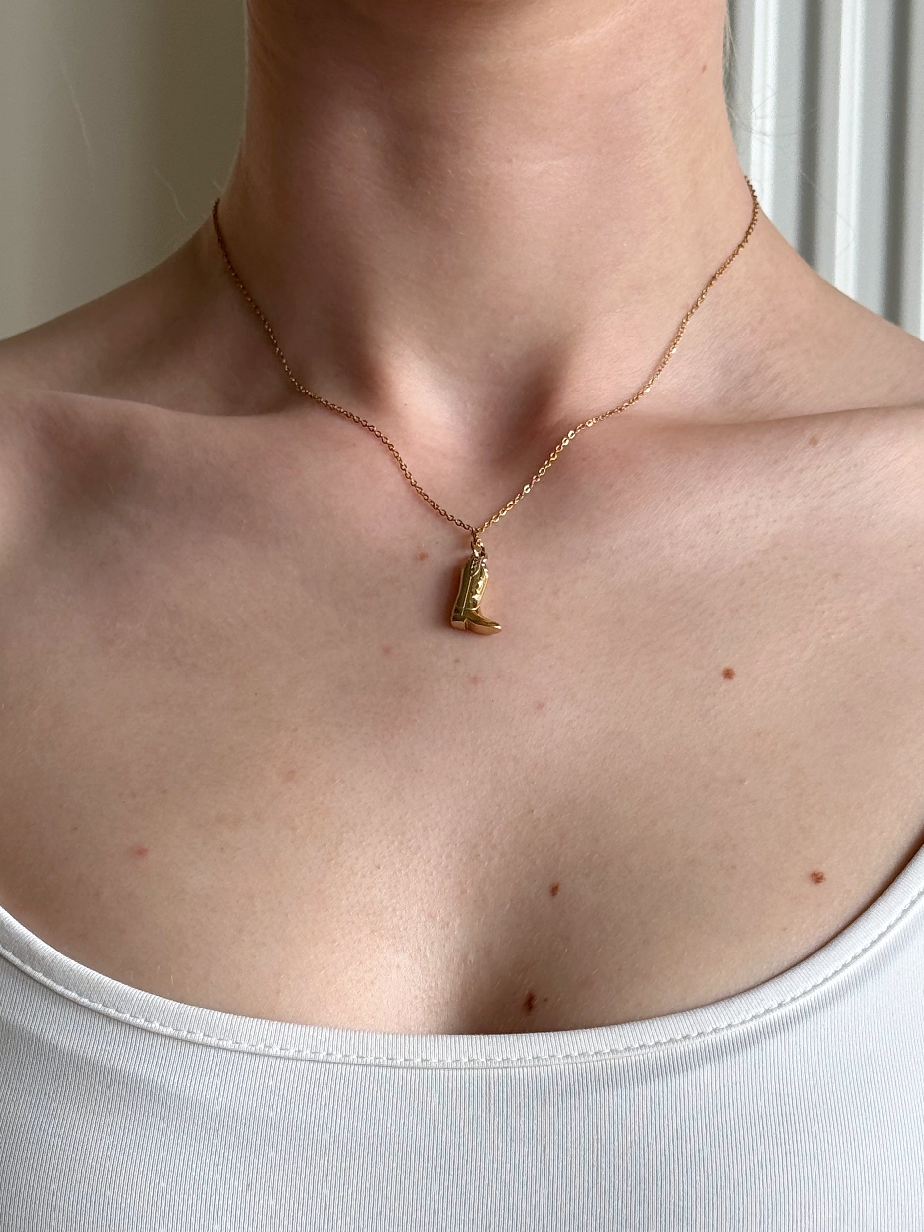 Gold stainless steel necklace with a cowgirl pendant on a girl wearing a white top.