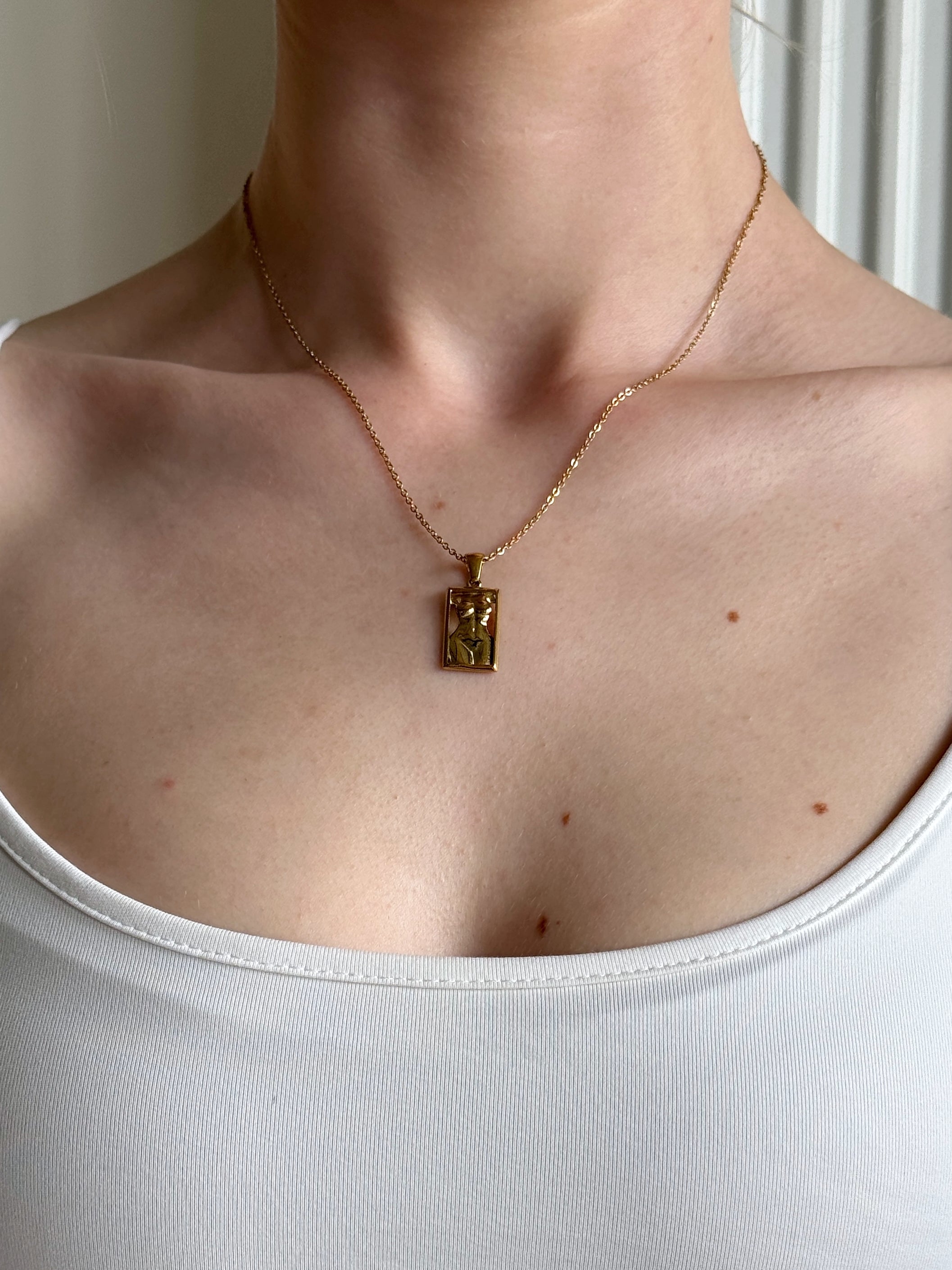 Necklace with a pendant worn by a person against a neutral background