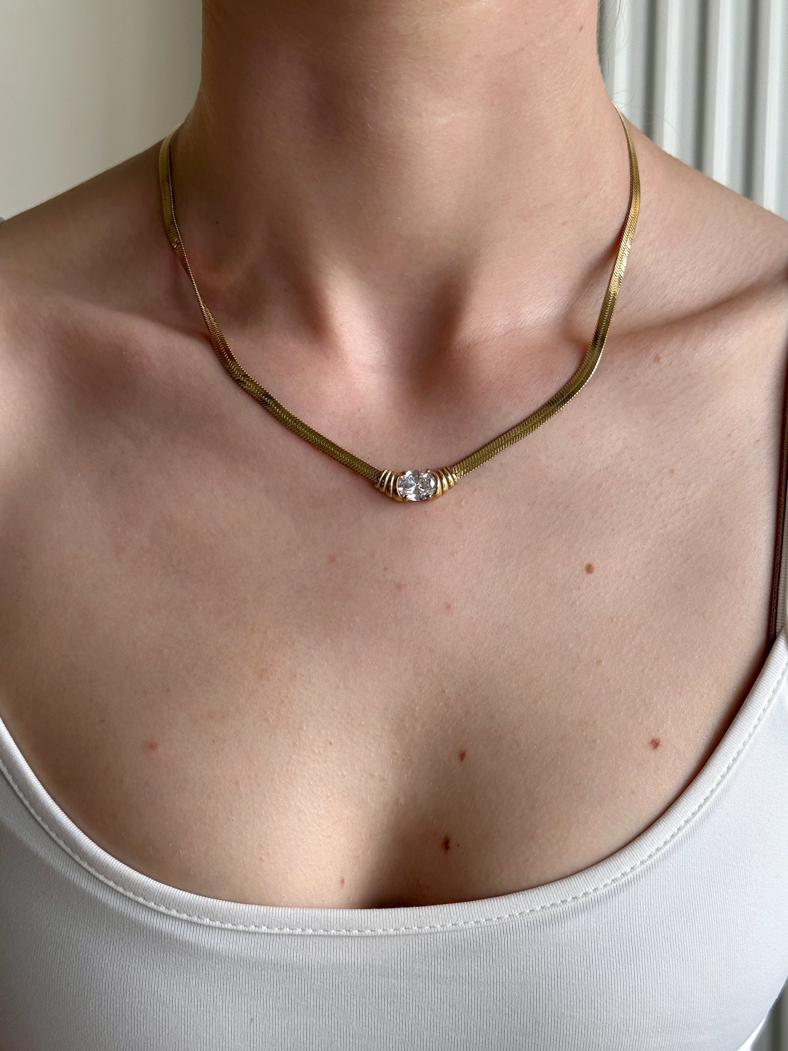 Close-up of a woman wearing a classic gold necklace with a clear pendant.