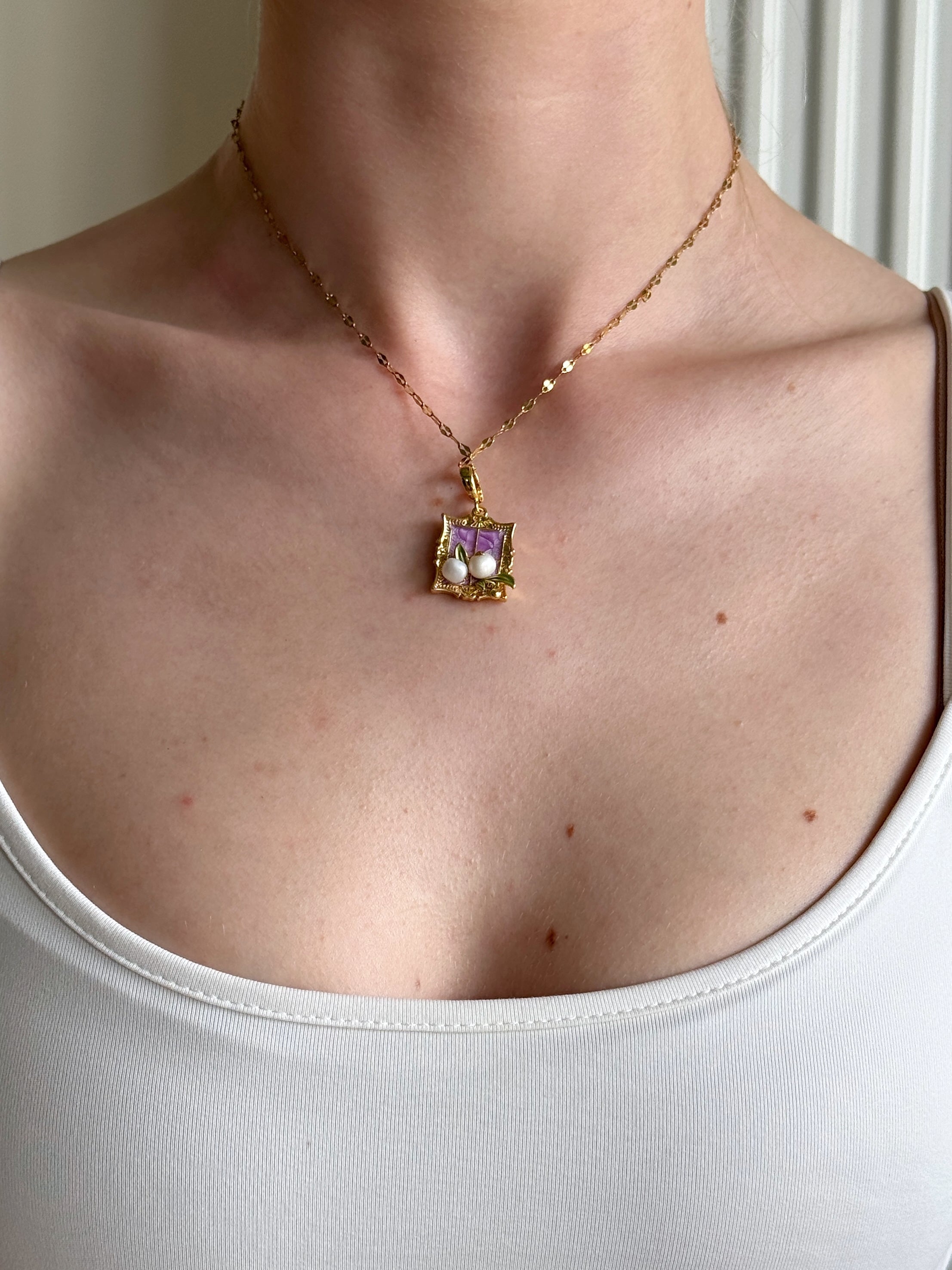 Necklace with a pendant worn by a person against a neutral background