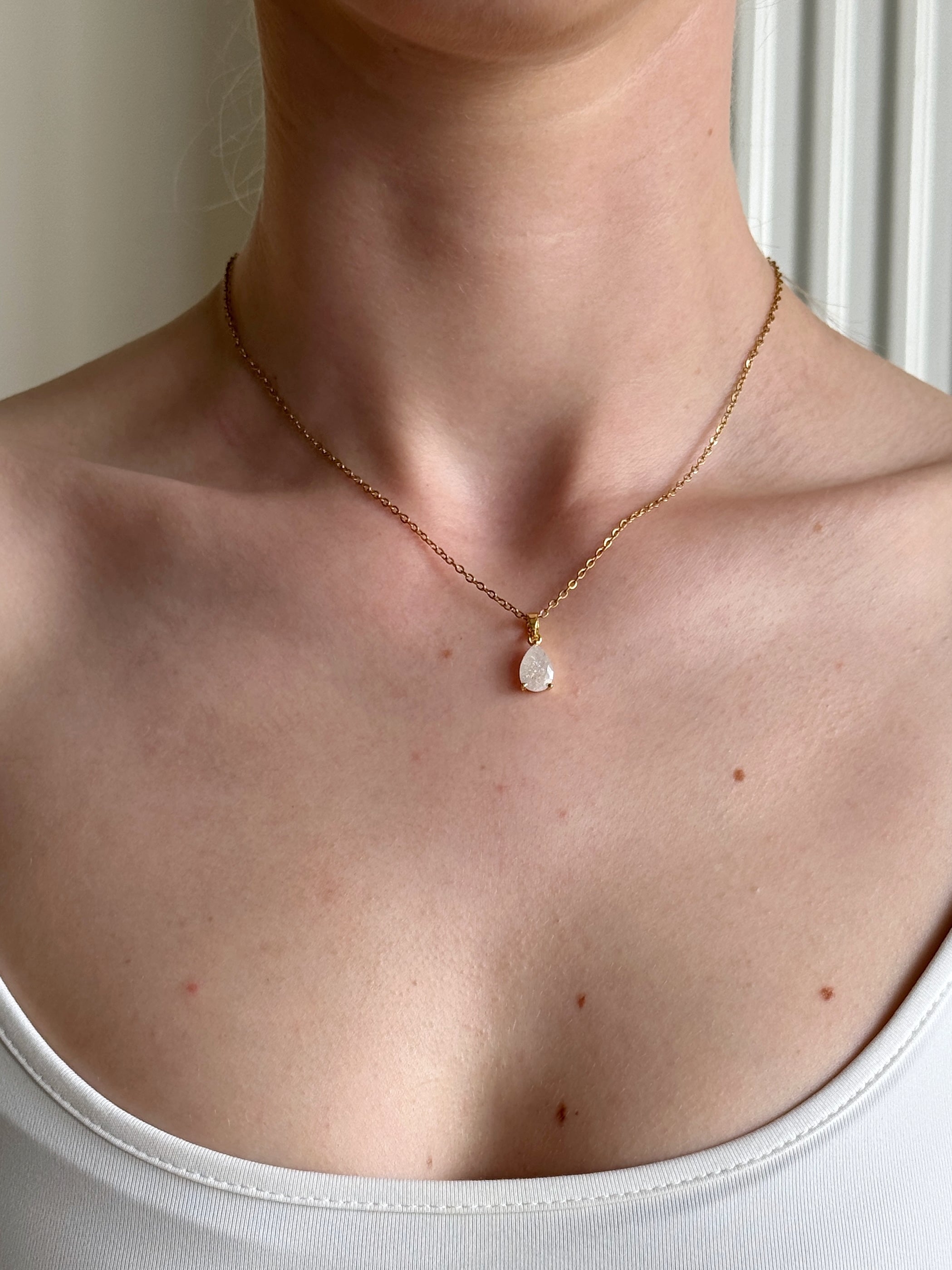 Necklace with a small pendant worn by a person against a neutral background
