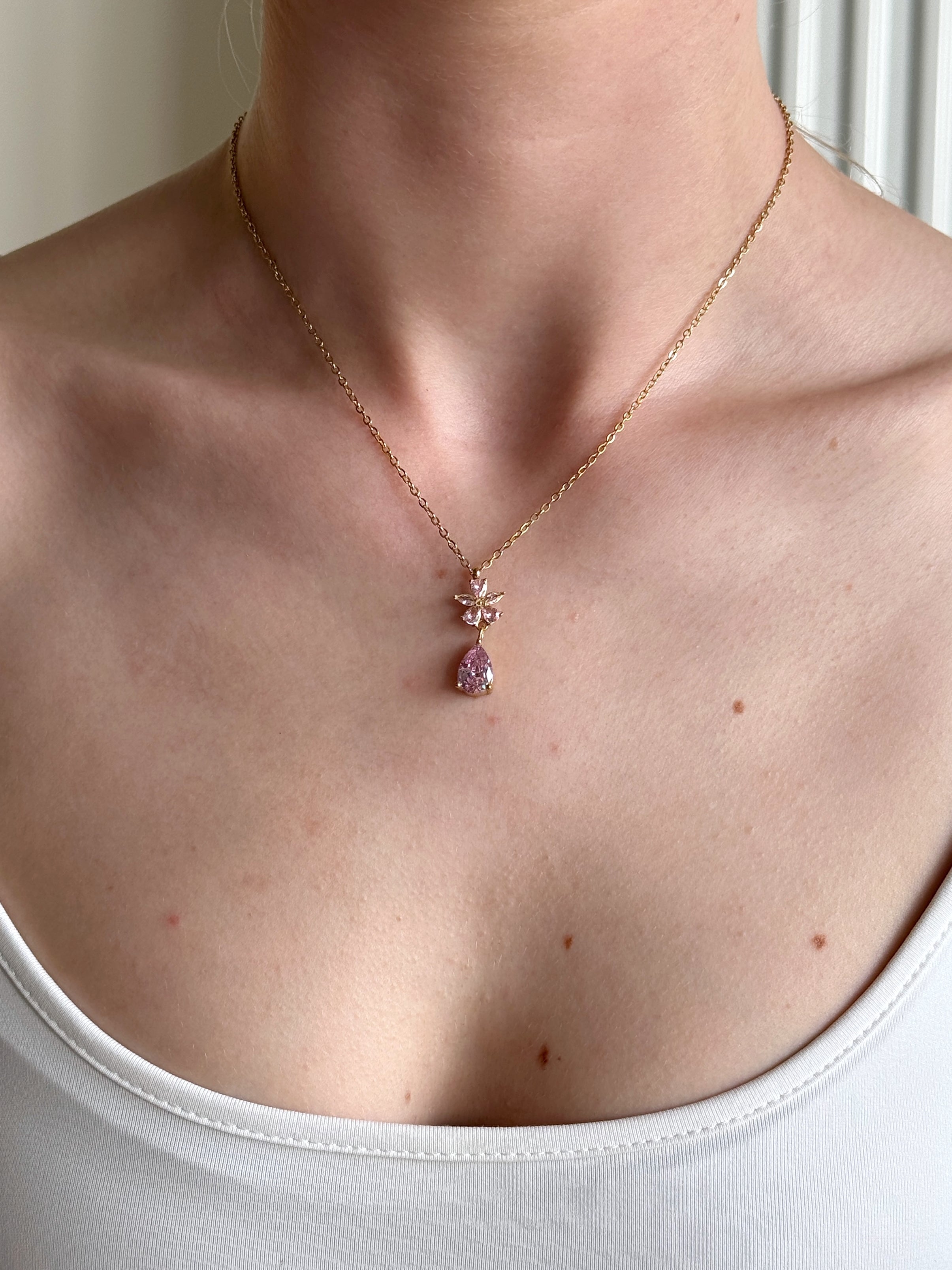 Necklace with a pink pendant worn by a person